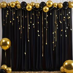 gold and black balloons are hanging from the curtain