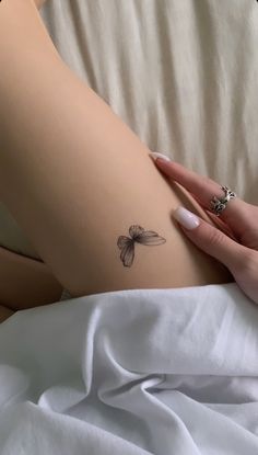 a woman's arm with a small butterfly tattoo on the left side of her thigh