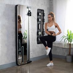 a woman is doing squats in front of a mirror with her reflection on the wall