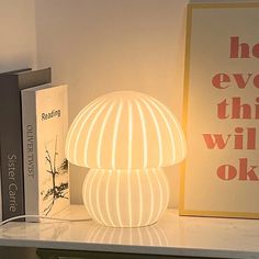 a white lamp sitting on top of a table next to books