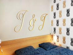 a bedroom with pineapple wallpaper and gold monogrammed letters on the wall