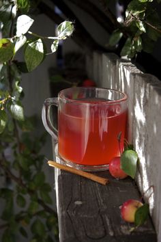 a glass cup filled with liquid next to an apple