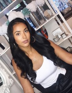 a woman sitting in front of a mirror wearing a white shirt and black skirt with fluffy pom poms on her head