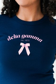 a woman wearing a blue shirt with pink ribbon on the chest and name delta gaannaa