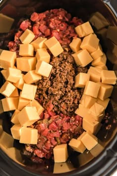 cubed cheese and ground beef in the crockpot with chili sauce on top