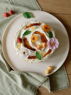 a white plate topped with a cake covered in icing and toppings next to cherries