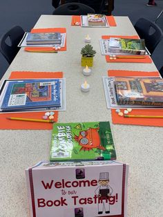 there is a table with books on it and a welcome book tasting sign at the end