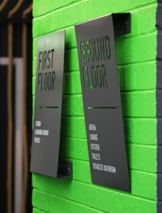 two signs on the side of a green building that says first floor and second floor