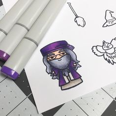 some markers and pens are laying on top of a piece of paper that has an image of a wizard