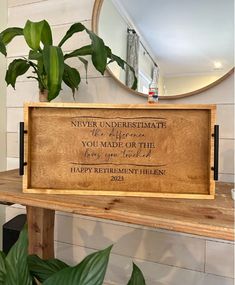 a wooden sign sitting on top of a table next to a potted green plant