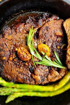 some meat and asparagus in a black bowl