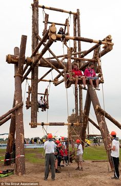 children are playing on the wooden structure at an amusement park while adults watch from behind