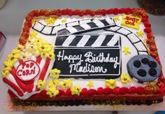 a birthday cake that is decorated with popcorn, soda and movie clapper on it