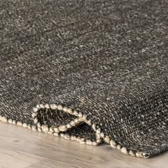 an area rug on the floor that has been made with dark colored wool and white beads