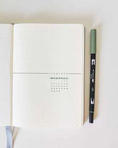 an open notebook with a green pen on the page and a black marker next to it