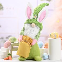 a stuffed rabbit with a green sweater and hat holding a carrot in it's hand