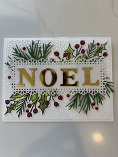 a christmas card with the word noel spelled in gold letters and holly berries on it