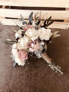 a bridal bouquet sitting on the ground in front of a wooden crate filled with flowers