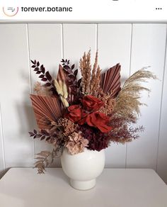 a white vase filled with lots of different types of flowers