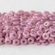 some pink beads are on a white surface and there is no image in the top right corner