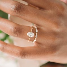 a woman's hand holding a ring with a diamond in it and pearls on the band