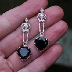 These skeleton and black heart earrings will be your new favourite.. they're already mine.  Elegantly gothic, two heart shaped black spinel hang from an intriquate and detailed skeleton.  Made in 100% recycled sterling silver. As each piece is made to order, please allow 2-3 weeks production time.   These earrings are made entirely by hand in Charlie's London workshop. Black Dangle Heart Pierced Earrings, Black Heart Charm Dangle Earrings, Black Gothic Earrings With Skull Print, Gothic Black Heart-shaped Earrings, Edgy Skull-shaped Earrings For Gift, Black Heart Earrings, Gothic Earrings, Black Spinel, Black Heart