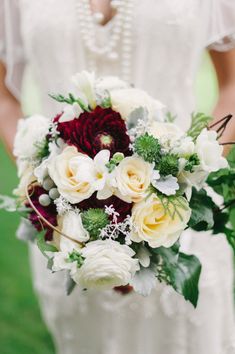 a bridal holding a bouquet of white and red flowers