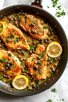 chicken with capers and lemons in a skillet on a marble countertop