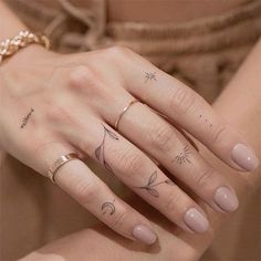 a woman's hand with three different tattoos on her fingers and the other finger