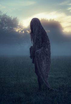 a woman standing in the middle of a field with her back turned to the camera