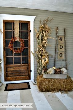 a front door decorated for fall with hay and pumpkins