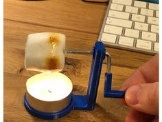 a person is lighting a candle in front of a computer keyboard on a wooden table