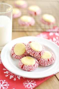 some cookies are on a white plate next to a glass of milk and a red napkin