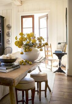 a table with two stools and a vase filled with yellow flowers