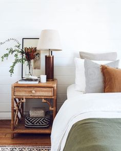 a bedroom with a bed, nightstand and plants on the side table next to it