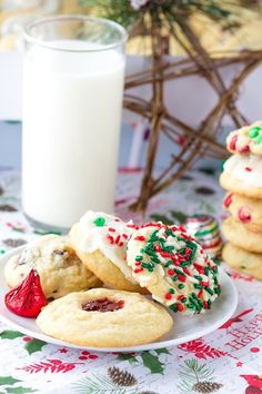 cookies with white frosting and sprinkles on a plate next to a glass of milk