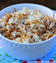 a white bowl filled with rice sitting on top of a blue and red table cloth