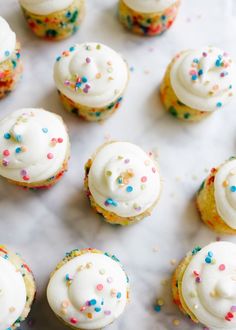 cupcakes with white frosting and sprinkles on a marble surface