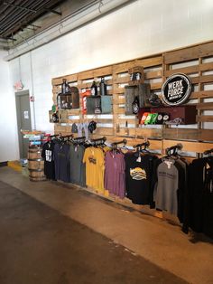 the inside of a store with shirts hanging on wooden pallets