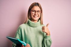 a woman wearing glasses giving the thumbs up sign while holding a folder in her hand