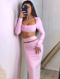 a woman taking a selfie while wearing a pink two piece skirt and crop top