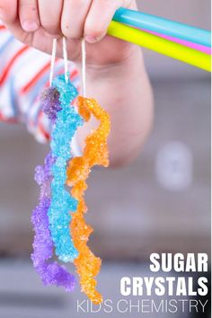 a child holding a rainbow colored candy bar with the words sugar crystals kid's chemistry written on it