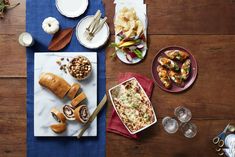 an overhead view of food and drinks on a table with blue napkins, wine glasses and plates