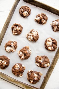 chocolate cookies with marshmallows are on a baking sheet