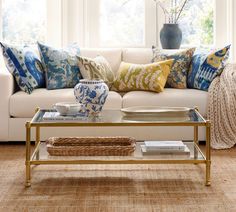 a living room with a couch, coffee table and vase on the end table in front of it