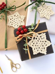 two wrapped presents with crochet designs on them, tied in twine and sitting next to scissors