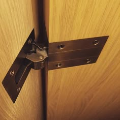 a close up of a door hinge with a wooden surface and metal latch on it