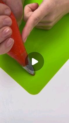 a person is cutting up a carrot with a sharp knife on a green mat that's being used as a garnish