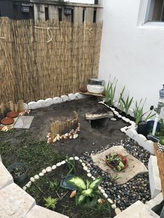 a small garden with rocks and plants in the center, next to a bamboo fence