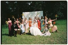 a group of people standing next to each other in front of a white wall with flowers on it